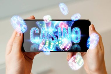 Online kumarhanenin yaratıcı geçmişi, bir adamın elinde neon kartları, çipleri, zarları olan bir akıllı telefon. Online kumar, bahis, poker konsepti. Boşluğu kopyala