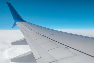 Bulutların üzerinde modern bir yolcu uçağının kanadı. Uluslararası kargo taşımacılığı, hava taşımacılığı, ulaşım. Boşluğu kopyala