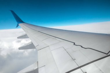 Bulutların üzerinde modern bir yolcu uçağının kanadı. Uluslararası kargo taşımacılığı, hava taşımacılığı, ulaşım. Boşluğu kopyala