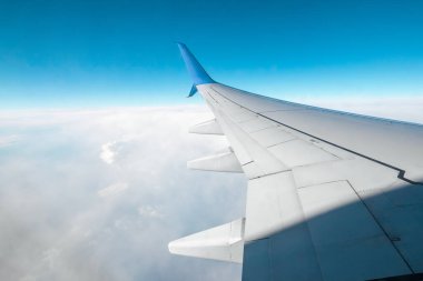 Bulutların üzerinde modern bir yolcu uçağının kanadı. Uluslararası kargo taşımacılığı, hava taşımacılığı, ulaşım. Boşluğu kopyala