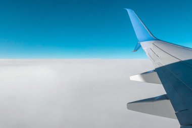 Bulutların üzerinde modern bir yolcu uçağının kanadı. Uluslararası kargo taşımacılığı, hava taşımacılığı, ulaşım. Boşluğu kopyala