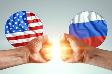 Erkek eller yumruklarını Amerika ve Rusya 'nın bayraklarına karşı gösteriyor. Güç mücadelesi kavramı, çıkar çatışması, savaş, yaptırımlar, soğuk savaş, ekonomik mücadele