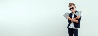 Hafif bir geçmişi olan zengin bir çocuk elinde bir tomar para tutuyor. Finansal eğitim, genç milyoner, yatırımlar, krediler, kazançlar, kâr payları. Broşür boş, site başlığı, kopyalama alanı