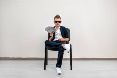 Hafif bir geçmişi olan zengin bir çocuk elinde bir tomar para tutuyor. Finansal eğitim, genç milyoner, yatırımlar, krediler, kazançlar, kâr payları. Boşluğu kopyala