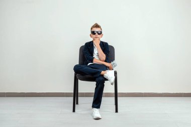 Hafif bir geçmişi olan zengin bir çocuk elinde bir tomar para tutuyor. Finansal eğitim, genç milyoner, yatırımlar, krediler, kazançlar, kâr payları. Boşluğu kopyala