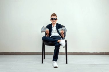 Hafif bir geçmişi olan zengin bir çocuk elinde bir tomar para tutuyor. Finansal eğitim, genç milyoner, yatırımlar, krediler, kazançlar, kâr payları. Boşluğu kopyala