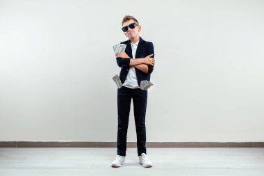 Hafif bir geçmişi olan zengin bir çocuk elinde bir tomar para tutuyor. Finansal eğitim, genç milyoner, yatırımlar, krediler, kazançlar, kâr payları. Boşluğu kopyala