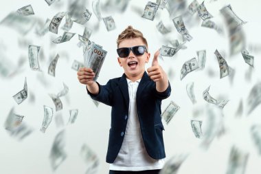 Gözlüklü, yakışıklı, zengin bir çocuk dolarları tutuyor ve düşen banknotların arkasından nasıl para kazanılacağını biliyor. Para yağmuru, mali eğitim, genç milyoner, yatırımlar, krediler, kazançlar