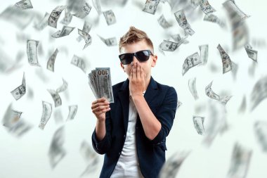 Gözlüklü, yakışıklı, zengin bir çocuk dolarları tutuyor ve düşen banknotların arkasından nasıl para kazanılacağını biliyor. Para yağmuru, mali eğitim, genç milyoner, yatırımlar, krediler, kazançlar.