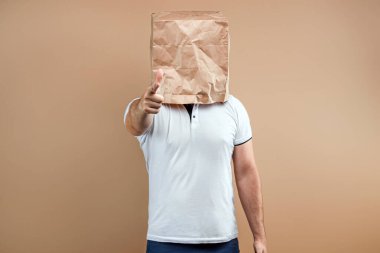 Erkekler kafalarına kese kağıdı geçirip seni işaret ederler. Sarı arkaplanda izole et, resimleri her yerde kullanmak kolaydır, boşluğu kopyala