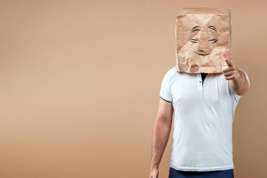 Erkekler kafalarına boyalı gözlerle bir kese kağıdı geçirip seni işaret ederler. Sarı arkaplanda izole et, resimleri her yerde kullanmak kolaydır, boşluğu kopyala