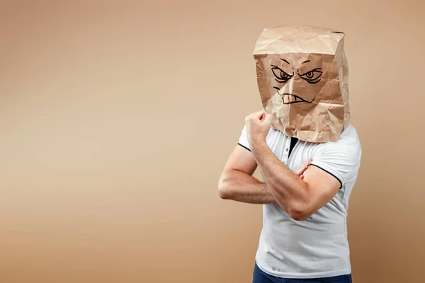 Men put a paper bag on their heads with a painted grinning face, demonstrate strength, biceps, motivation. Isolate on yellow background, images are easy to crop for use anywhere, copy space