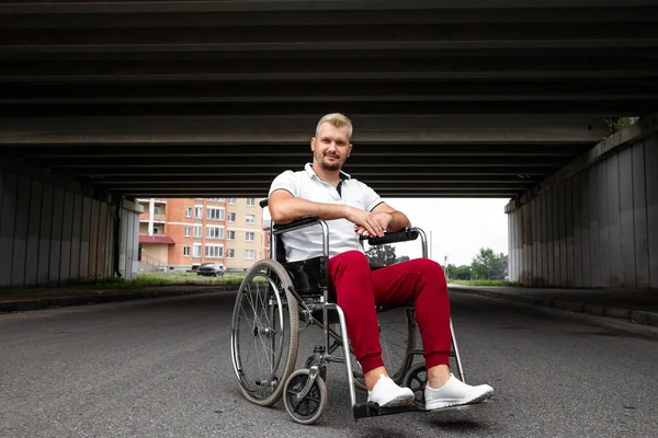 A disabled man sits in a wheelchair on the street. The concept of a wheelchair, disabled person, full life, paralyzed, disabled person, health care