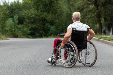 Engelli bir adam sokakta tekerlekli sandalyede oturuyor. Tekerlekli sandalye konsepti, engelli insan, hayat dolu, felçli, engelli insan, sağlık hizmetleri