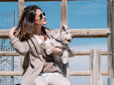 Schnauzer köpeği olan kadın trabzanda oturuyor.