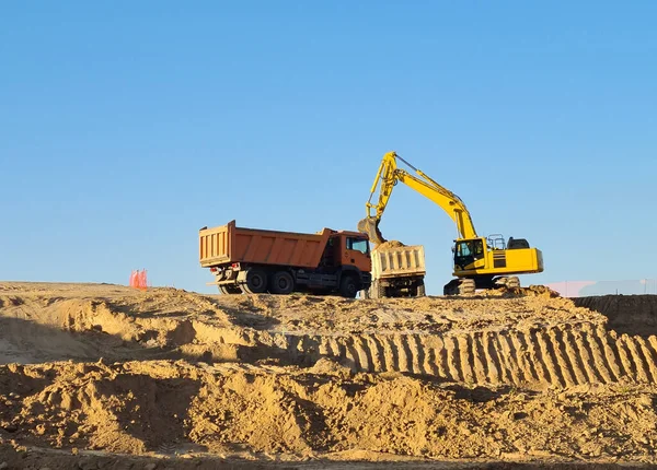 在阳光灿烂的日子里 挖掘机在建筑工地用两辆卡车挖掘 在马德里Valdebebas工作的挖掘者 — 图库照片