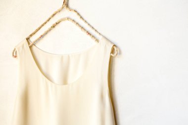 Beyaz bir duvardaki askıda asılı bej ya da beyaz bir atlet. Kapat ve boşluğu kopyala.