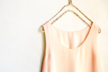 Beyaz bir duvardaki askıda asılı açık pembe bir atlet. Kapat ve boşluğu kopyala.