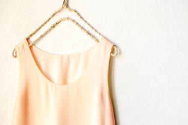 Beyaz bir duvardaki askıda asılı açık pembe bir atlet. Kapat ve boşluğu kopyala.