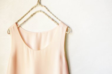 Beyaz bir duvardaki askıda asılı açık pembe bir atlet. Kapat ve boşluğu kopyala.