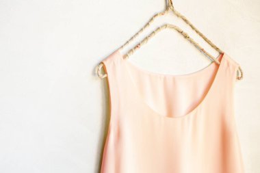 Beyaz bir duvardaki askıda asılı açık pembe bir atlet. Kapat ve boşluğu kopyala.