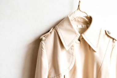 Beyazın üzerine izole edilmiş bej renkli bir trençkot..