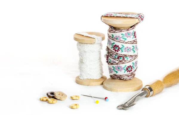 Vintage lace on the wooden bobbin ,ruler ,wood buttons and marking pins on white background and copy space.