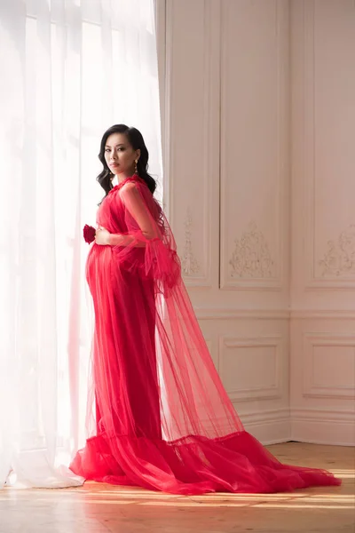 在室内穿着红色长裙的美丽的亚洲孕妇 — 图库照片