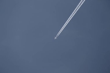 Beyaz, bulutsuz bir gökyüzünde, bir uçağın arkasında zıtlaşıyor.