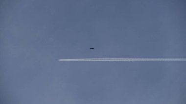 Beyaz, bulutsuz bir gökyüzünde, bir uçağın arkasında zıtlaşıyor.