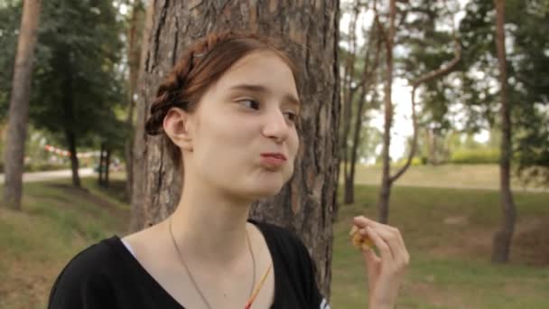 Het meisje eet candy apple en kijkt naar de camera. — Stockvideo