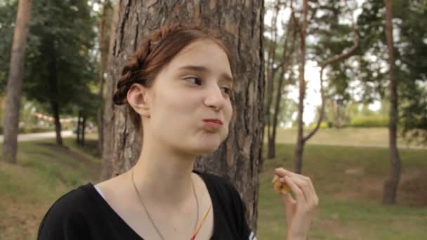 The girl eats candy apple and looks to the camera. — Stock Video