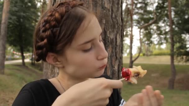 Весела дівчина прибирає яблуко з палички . — стокове відео