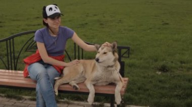 Bir köpek bir bankta okşayarak bir kız.