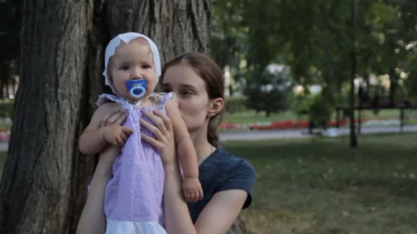 Une très jeune nounou ayant une petite fille avec une sucette sur les genoux 