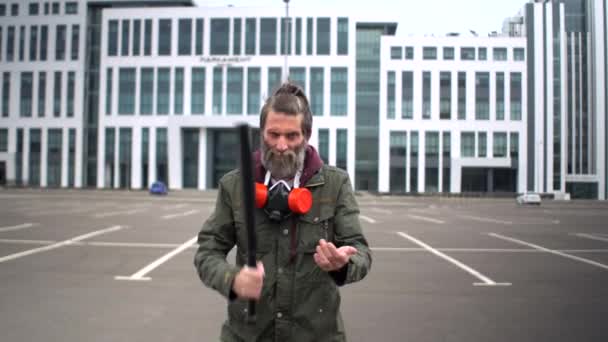 Concetto proteste sociali durante la pandemia codarda, sopravvivenza isolata, minacce di violenza. Strano uomo barbuto di mezza età in parcheggio frangia pipistrello sul palmo della mano e guarda minacciosamente alla fotocamera — Video Stock