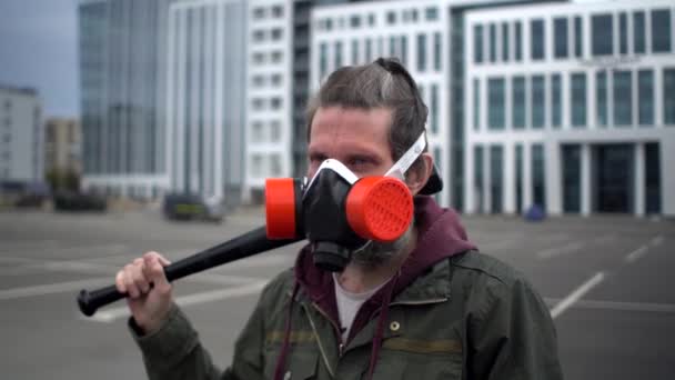 Begreppet sociala protester under covid pandemi, överlevnad i isolering, hot om våld. Konstigt medelålders man i parkering respirator med respirator och baseball bat på axeln rör sig runt — Stockvideo