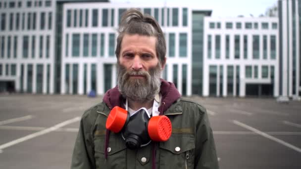 Strange bearded middle-aged man in parking looks judgmental and puts on a respirator. Concept social protests during covid pandemic, survival in isolation, threats of violence — Stock Video