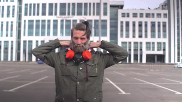 Social protest during covid pandemic concept. Strange bearded middle-aged man puts on respirator and gazes to camera — Stock Video