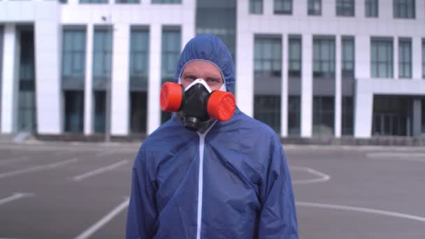 Skäggig man med respirator och skyddsdräkt ser ut till kameran Närbild — Stockvideo