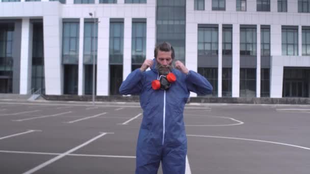 Bearded man puts on respirator and hood of protective suit — Stock Video