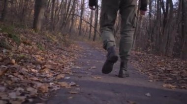 Askeri kargo pantolonu ve asker botu giyen erkek ayakları orman parkında tek başına dolaşırken kordemik koronavirüs kilitlenmesi sırasında...