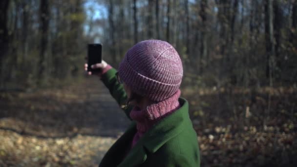 Μεσήλικη γυναίκα με γυαλιά βγάζει selfie στο πάρκο του δάσους στη μοναξιά κατά τη διάρκεια του αποκλεισμού του covid panemic coronavirus — Αρχείο Βίντεο