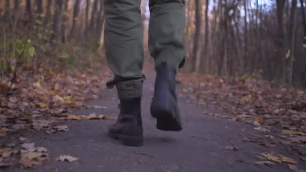 Mannelijke benen in militaire vrachtbroek en soldatenlaarzen lopen alleen in het bospark tijdens hevige pandemische coronavirus lockdown — Stockvideo