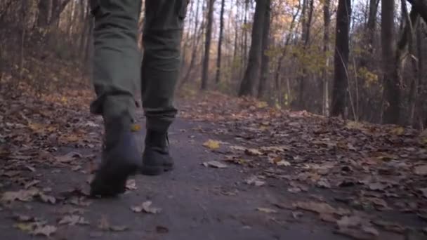 Мужские ноги в военных брюках и солдатских сапогах прогуливаются в лесном парке во время пандемической блокировки коронавируса — стоковое видео