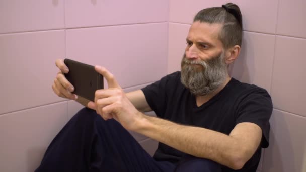 수염을 기른 중년 남자 암호 장수 화장실에 있는 모든 사람들로부터 숨어 스마트폰으로 암호화 된 화폐를 교환한다 — 비디오