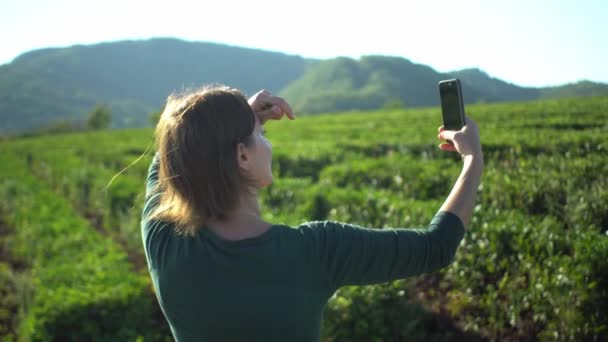 Beatiful donna che fa selfie da smartphone sul campo fresco piantagione di tè verde con sfondo di montagna — Video Stock