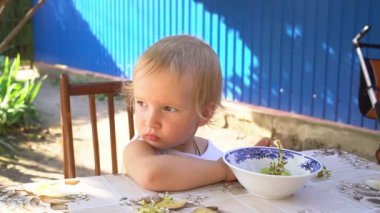 Yazın evin bahçesindeki masada üzüm yiyen küçük bir sarışın.