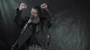Deri ceketli sakallı, kıllı rock müzisyeni bir öpücük yolluyor, yumruklarını kaldırıyor ve sahneyi siyah perde arkasında bırakıp gidiyor.