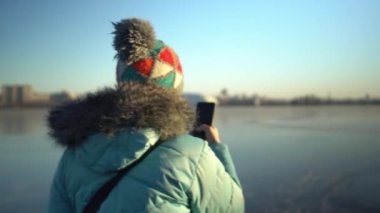 Mavi ceketli ve şapkalı yetişkin bir kadın kışın buzda duruyor.